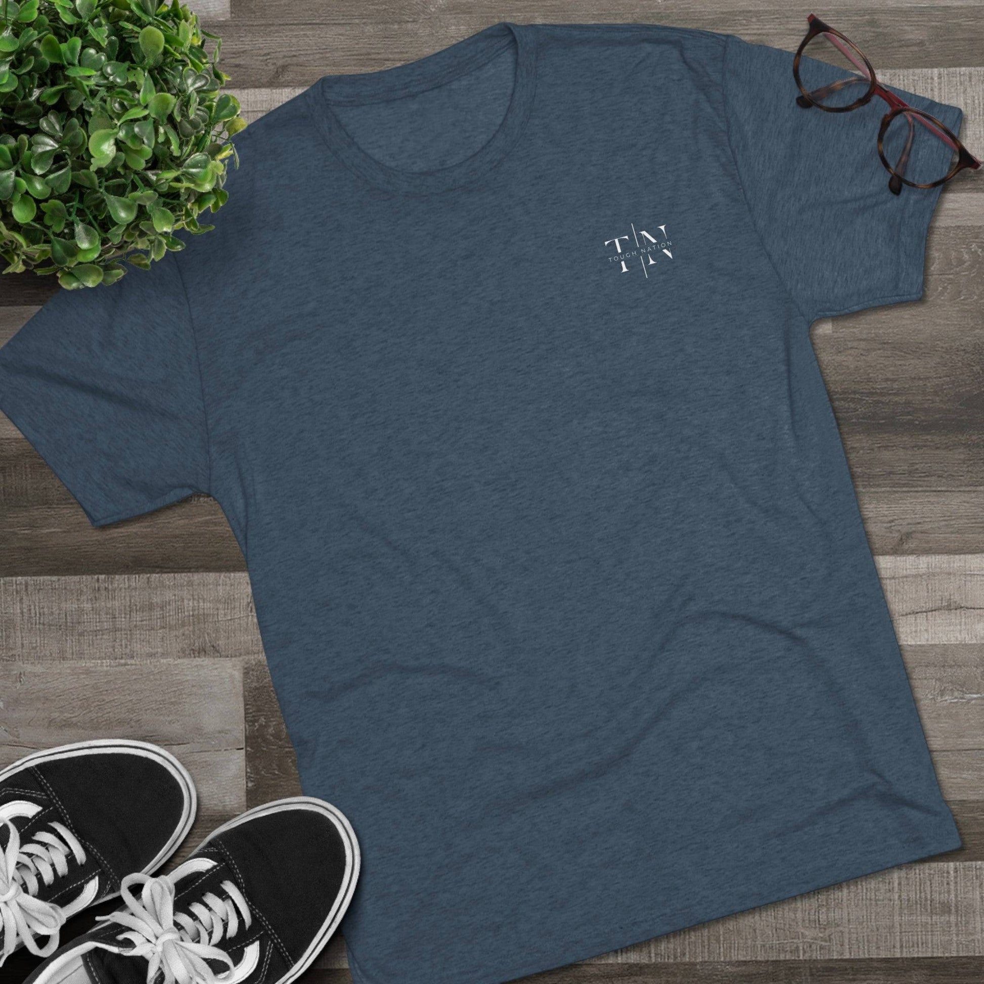 A lifestyle image showcasing a indigo Christian fitness shirt (left side logo) alongside athletic shoes, leaves, and glasses, perfect for an active lifestyle