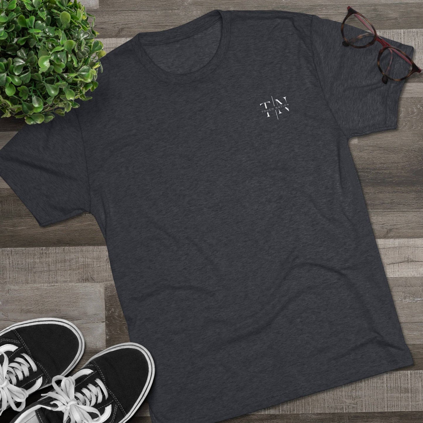 A lifestyle image showcasing a vintage navy Christian fitness shirt (left side logo) alongside athletic shoes, leaves, and glasses, perfect for an active lifestyle